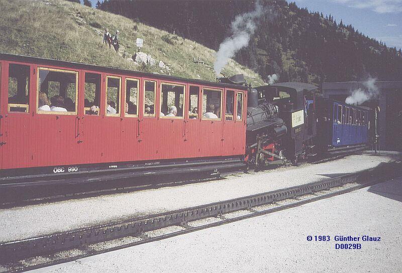 999.104  Berg-Primel  mit roten Wagen und 999.102  Enzian  mit blauen Wagen warten auf ihrer Bergfahrt im Sommer 1983 in der Ausweichhaltestelle Schafbergalpe auf einen Gegenzug. 