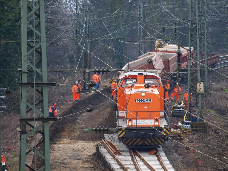Aachen Westbahnhof am 22.03.2009 an der Rampe der Strecke nach Montzen. Ein Gleisbauzug kippt in das gerade ausgebaggerte Gleisbett neues Fllmaterial. Im hintergrund kann man noch einen 2Wegebagger sehen der den letzten Waggon mit dem alten Schotter beld.