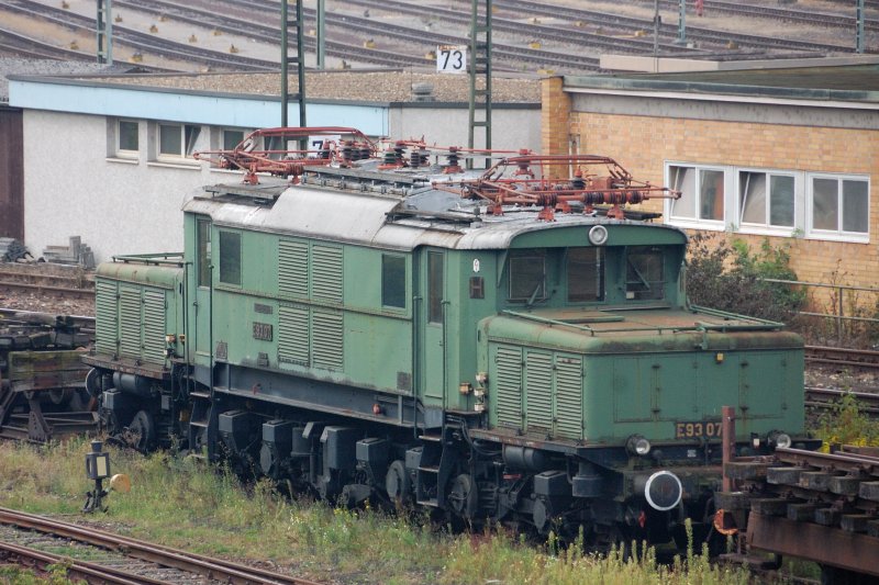 Abgestellt in Kornwestheim: E93 07 der IG Deutsches Krokodil. Sie wurde innerhalb der 2. Bauserie unter der Fabriknummer 4961 gebaut und am 6. Mrz 1937 an die DRG geliefert. ber 50 Jahre stand sie in Kornwestheim in Dienst. Sie war hauptschlich auf den Strecken Kornwestheim - Ulm und Plochingen - Tbingen im Einsatz. Die Zeit ging an ihr aber nicht spurlos vorbei. Ernchterung, nachdem im Februar 1986 der Kostenvoranschlag fr die erforderliche Hauptuntersuchung kam. Trotz Abzug aller in Eigenleistung mglichen Arbeiten sollten demnach noch 150 000.- DM aufgebracht werden. So wurde nach einem entsprechenden Ersatz geschaut. Gefunden wurde er in 194 579 sowie der 194 581 als Ersatzteilspender.  Seit E93 07 im Zuge der Reaktivierung der Ellokwerkstatt beim Bw Kornwestheim ihren schtzenden Schuppenplatz rumen musste, ist sie bei der Gesellschaft zur Erhaltung von Schienenfahrzeugen e.V. auf deren Gelnde am Kornwestheimer Rangierbahnhof untergebracht.
