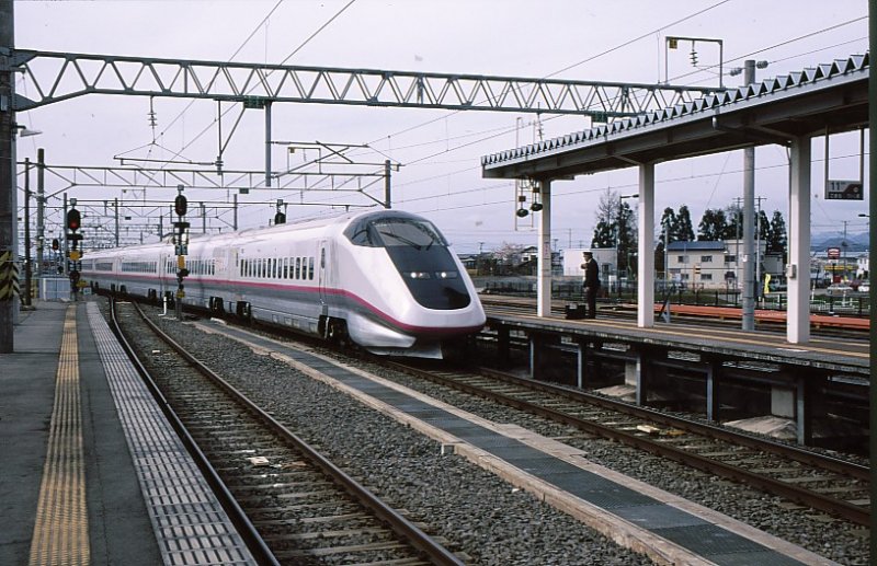 Akita Shinkansen - Serie E3 (im Bild: Endwagen E322-19).Die Shinkansen dieser Linie (namens KOMACHI) fahren mit den Zügen der Hauptlinie nach Norden gekuppelt bis Morioka, kommen dort von der Hochgeschwindigkeitsstrecke herunter und benützen dann die 127km lange, auf 1435mm umgespurte alte Linie über die Berge nach Akita. Aufnahme in Ômagari, 22.April 2003.   