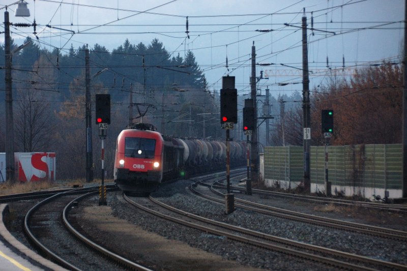 Als ziehe sie verschieden schmutzig-bunte  Watte -Bllchen an einer Perlenkette hinter sich her... 1116 148-6 vor einem Gterzug aus berwiegend Kesselwagen. (Brixlegg, 02.12.2008)