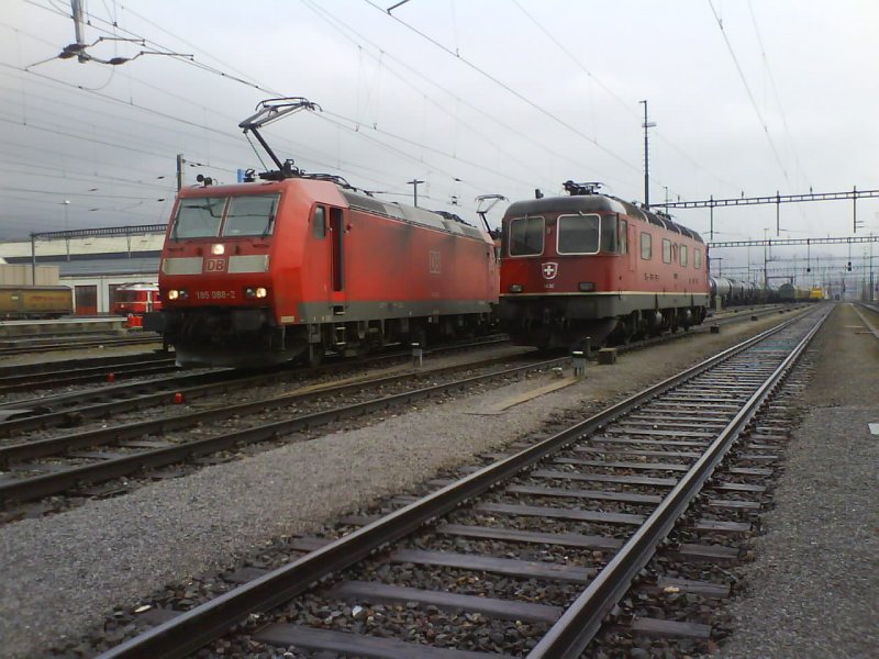 Alt trifft Neu. Links wartet eine DB Br 185 mit einem lzug auf den Abfahrtsbefehl, whrend die RE 6/6 abgestellt im Regen steht. Landquart 03.04.07