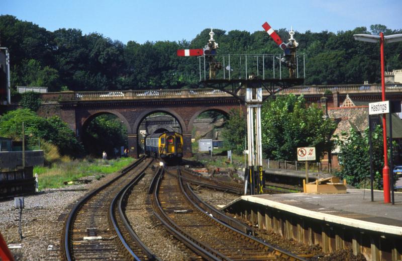 Am 10. August 1987 zieht ein EMU (nein: kein Laufvogel, sondern eine  Electrical Multiple Unit , also ein ET) bei der Ausfahrt aus dem Bahnhof Hastings in Richtung Bexhill/Eastbourne mit seinem Stromabnahmeschuh einen schnen Lichtbogen aus der 750-Volt-Gleichstrom-Stromschiene - Britzel!!! - Aufnahme: Minolta CLE; Leitz Tele-Elmarit-M 2,8/90 mm; Film: Fuji RD 100 (CT)