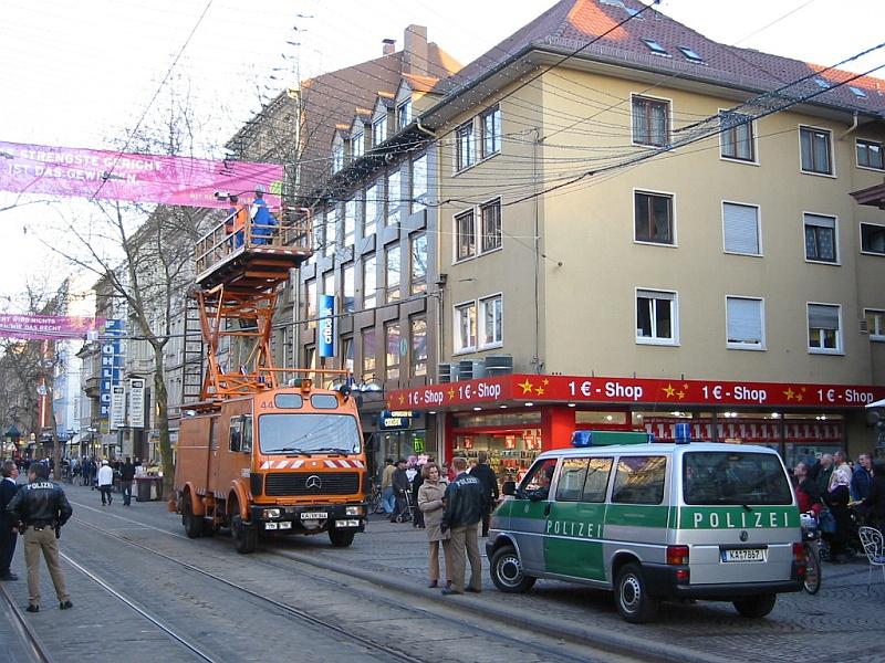 Am 15.03.2005 sorgte ein Problem mit der Oberleitung in der Kaiserstrasse (Fugngerzone und zugleich Rennpiste fr viele Linien) bei der Haltestelle Marktplatz fr Stress, und das im Feierabendverkehr. Es waren wohl Teile der noch installierten Weihnachtsbeleuchtung auf die Oberleitung gefallen. Glcklicherweise gibt es eine Ausweichstrecke, die die Bahnen nutzen konnten. Der Oberleitungstrupp der VBK war aber auch schnell zur Stelle. Die Polizei sicherte die Stelle ab, weil ein einzelnes Kabel (nicht im Bild) herunter baumelte.