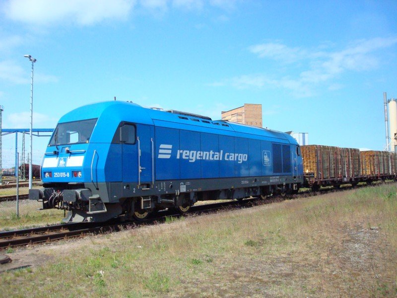 Am 18.05.08 war die 253 015-8 der Regental Cargo im Industriegebiet von Wismar mit einem langen Holzzug unterwegs.