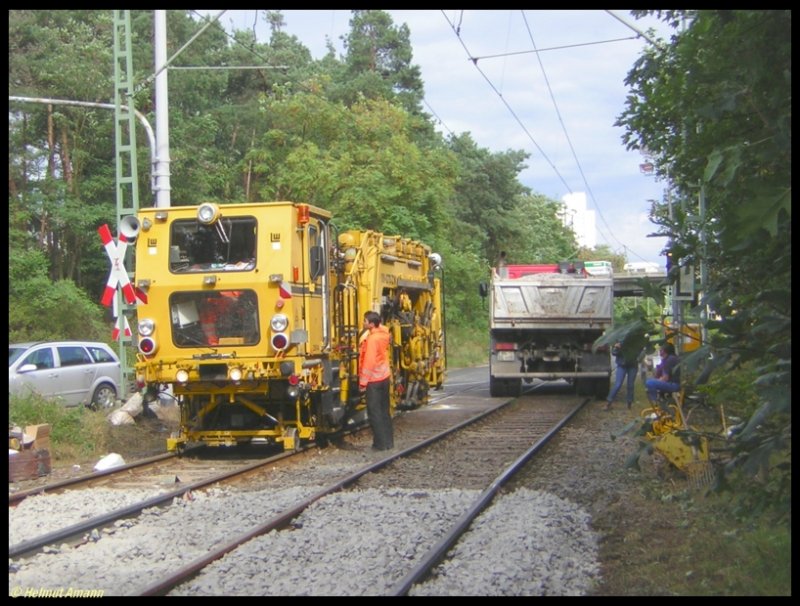 Am 20.08.2006 stand die Gleisstopfmaschine hinter dem Bahnbergang zwischen den Haltestellen Kiesschneise und Waldau bereit, die Arbeit an dem erneuerten Gleisabschnitt aufzunehmen, der deutlich erkennbar wie mit dem Lineal gezogen vor der Maschine beginnt.