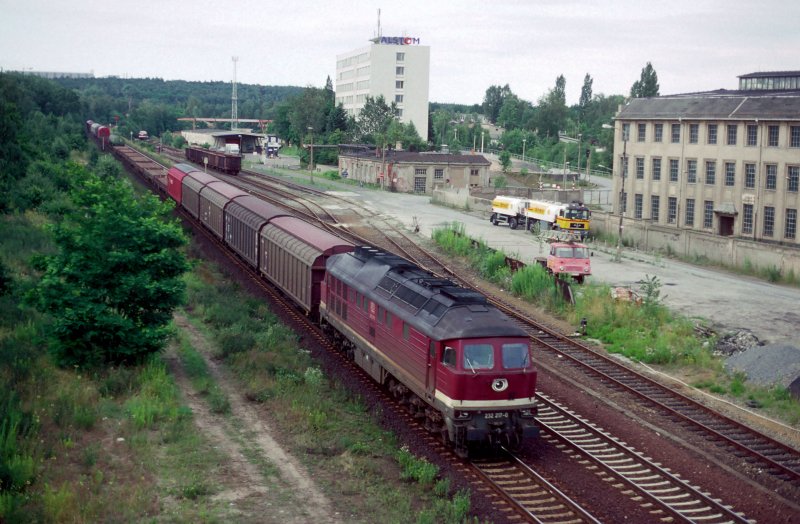 Am 9. Juli 1999 faehrt 232 217-0 mit einer Gueterzug aus Loebau und Bautzen an Dresden Industriegelaende vorbei. Im Hintergrund wartet ein DR-V180 auf der Schrotthaendler.