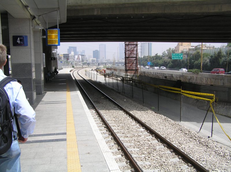 Am Bahnsteig 4 in T.A. Ha'Hagana blicken wir nach Norden. Die Strecke fhrt hier in Mittellage zwischen den 6spurigen Richtungsfahrbahnen des Ayalon Highway, sowie paralell zum Ayalon Chanal durch Tel Aviv. Die Strecke ist zweigleisig und wird aktuell auf drei Gleise ausgebaut. Rechts sehen wir den Neubau des Richtungsgleises nach Moshe Dayan sowie den Bau des Bahnsteiges 5, welcher aus Platzgrnden ber den Kanal auskragt.