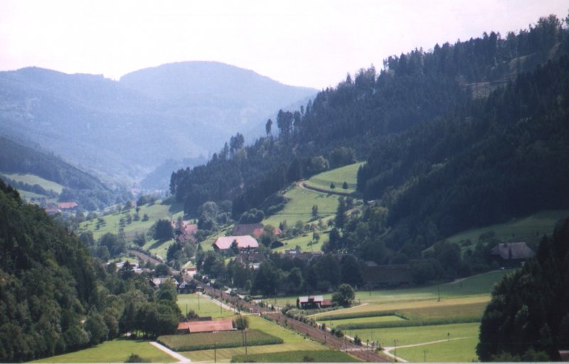 An der Schwarzwaldbahn: 
Im Gelnde (IV): In Hausach biegt die Schwarzwaldbahn in einem scharfen Bogen nach Sden. Hier blicken wir bei km 34 in das Tal der Gutach. Im Hintergrund ist der ca. 900 Meter hohe Schloberg
zu erkennen. Hinter ihm befindet sich die letzte Schleife im Seelenwald, wo die Bahn ca. 650 Hhenmeter erreicht. Etwas links 
der Bildmitte ist auch die Burg der Stadt Hornberg zu sehen.  