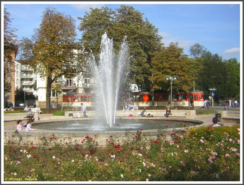 Anlsslich des Frankfurter Tages der Verkehrsgeschichte am 30.09.2007 pendelten zwei historische Straenbahnwagen zwischen Zoo und Schwanheim als Zubringer zum Verkehrsmuseum. Bei einem handelte es sich um den Triebwagen 112 (ex 812 Baujahr 1963 DWAG) der Bauart N, hier bei der ersten Fahrt dieses Tages in der Wendeschleife am Zoo (Alfred-Brehm-Platz) in Rosen eingebettet zu sehen. Auf Grund des an dem Tag herrlich milden Wetters sassen viele Menschen draussen an dem Brunnen in der Mitte des Platzes und genossen den schnen Sptsommertag.