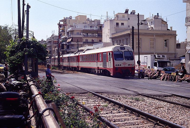 Athen, Po. Odos Lission. Der MAN-VT hat den etwas archaischen �berweg mit hebbaren Seilschranken passiert und f�hrt gleich in den Bf Athen Peloponn. ein (sept. 2004). Seit dem 5.04.2005 sollte die Regelspurneubaustrecke nach K�rinthos in Betrieb sein, bei der OSE ist aktuell im Internet aber nichts davon zu lesen.