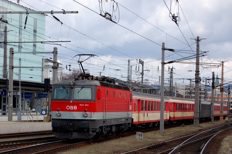 Auch schon mit kleiner Betriebsnummer fhrt die 4. ihrer Baureihe (1044) mit einem  Schlieren-Wagen-Zug  in Bahnsteig 7 Linz Hbf ein. Wie in sterreich blich bei dieser Baureihe mit  Standlicht . Als Farbtupferl inmitten von jaffa-orangenen Wagen ein ursprungslackierter, tannengrner  Schliere .
