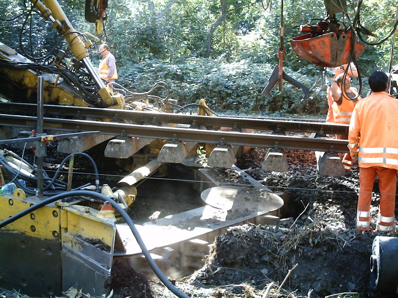 Auf dem Foto sieht man, wie der 'Bagger' den alten Unterbau wegbaggert, an eine Folie ausgerollt, und der gereinigte Schotter wieder verlegt wird.

Diejenigen, die mehr Fotos von dem Bauzug haben wollen, mailen mich bitte an.
