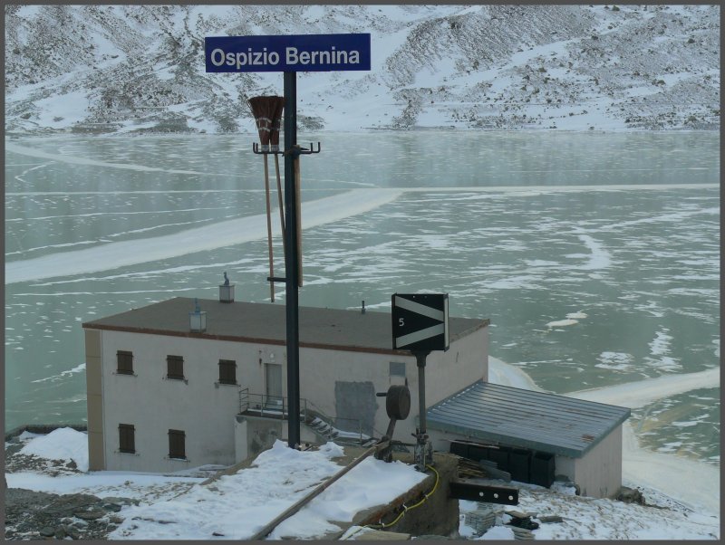 Ausblick durch die Scheibe eines Panoramawagens (gut geheizt) in der Station Ospizio Bernina 2253m/.M. Dank der eisigen Temperaturen von -25 Grad im Oberengadin ist der Lago Bianco praktisch schwarz gefroren. Wegen des stetigen Windes hlt sich der Schnee nicht auf der Eisoberflche. (15.11.2007)