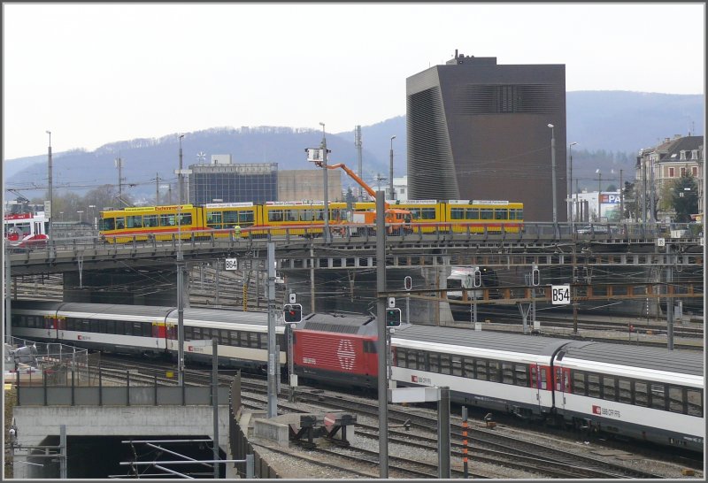 Bahnhof Basel SBB mit einem ausfahrenden IC mit Re 460 und Verstrkungswagen am Schluss. Auf der Brcke eine Be 4/8 und ein Be 4/6 der BLT 200er Serie. Dahinter erhebt sich das von den bekannten Basler Architekten Herzog & De Meuron entworfene Zentralstellwerk. 08.04.2008)