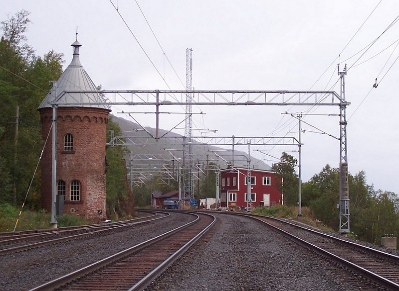 Bahnhof Rombak 17 km von Narvik am 05.09.2007, nett ist der alte Wasserturm, obwohl hier schon 80 Jahre keine Dampflocks fahren. Besonderheit: Der Bahnhof hat zur Zeit keinen Zugangsweg, man mu etwa 300 m zwischen den Gleisen auf dem Schotter gehen, die hier weit auseinander liegen oder ganz rechts auf dem Kabelkanal.