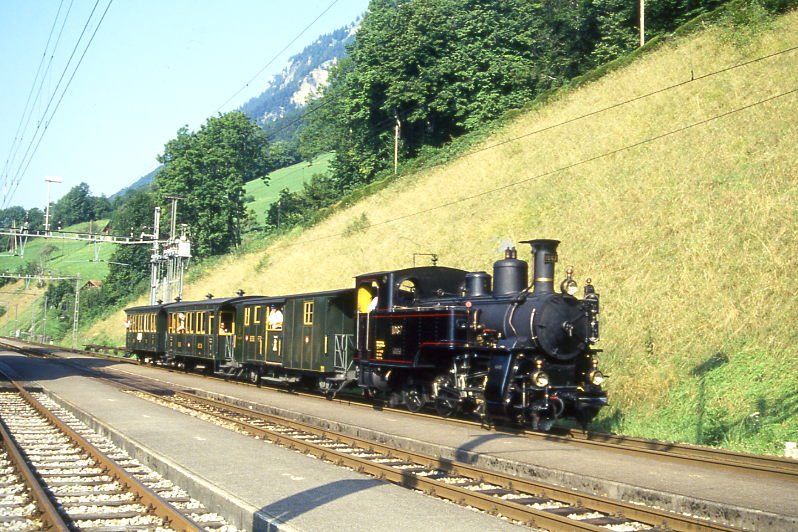 BDB Ballenberg Dampfbahn Dampfzug 32021 von Interlaken Ost nach Brienz am 06.08.1994 Durchfahrt Ringgenberg mit Zahnrad-Dampflok HG 3/3 1067 - F 51 - BC 28 - C 31. Hinweis: gescanntes Dia.
