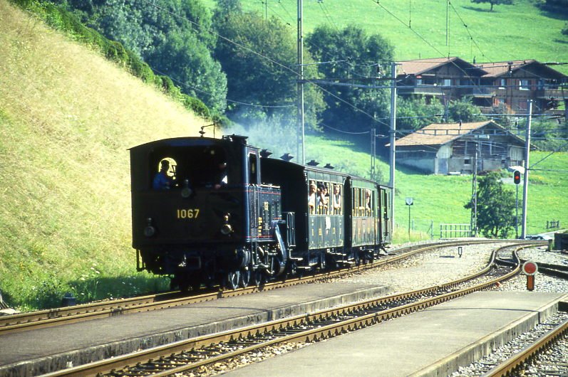 BDB Ballenberg Dampfbahn Dampfzug 32022 von Brienz nach Interlaken Ost am 06.08.1994 Durchfahrt Oberried mit Zahnrad-Dampflok HG 3/3 1067 - C 31 - BC 28 - F 51. Hinweis: gescanntes Dia.
