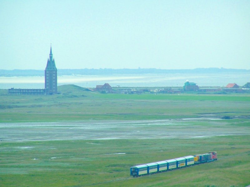 Bei nakaltem, trben Wetter wird ein  zu 100% ausgelasteter Personenzug Richtung Hafen gezogen; dahinter Westturm und im Hintergrund die Nachbarinsel Spiekeroog (06-09-02)