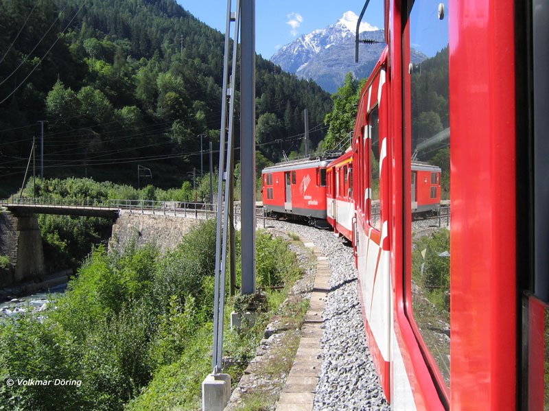 Beim Blick zurck aus dem in Richtung Brig talwrts fahrenden Zug, der soeben auf einer kleinen Brcke die Mattervisp berquert hat, spiegelt sich der schiebende Gepcktriebwagen Deh 4/4 im Fenster und im Hintergrund grt der auch im Hochsommer schneebedeckte Gipfel eines Viertausenders - 17.08.2005
