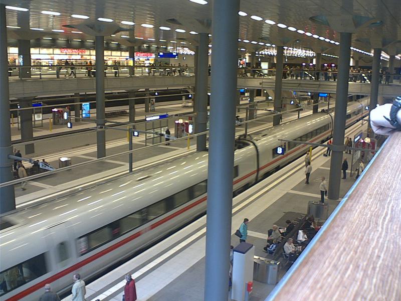 Berlin Hauptbahnhof - ein Bild aus der Mitte auf die untere Ebene. Pulsierendes Leben im erstarrten Zustand. Zu sehen sind Mittelwagen des ICE-T