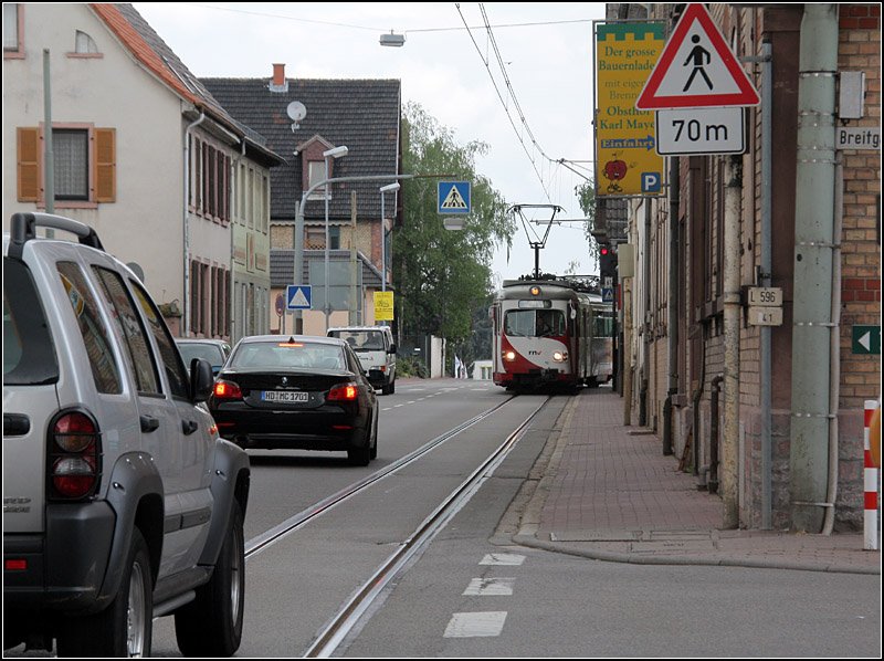 Bild 1: Pltzlich kommt da eine Straenbahn entgegen. Die OEG-Strecke Heidelberg - Weinheim luft meistens auf eingleisigem Bahnkrper neben der stark befahrenen Bundesstrae 3. Nur in der Ortsdurchfahrt Grosachsen wird es sehr eng, die eingleisige Strecke liegt da in der Straenfahrbahn, die Bahnen in Richtung Heidelberg mssen da dem Autoverkehr entgegenfahren, der trotz Gegenverkehr zum Teil auf die andere Fahrbahn ausweichen muss. 23.04.2009 (Matthias)

