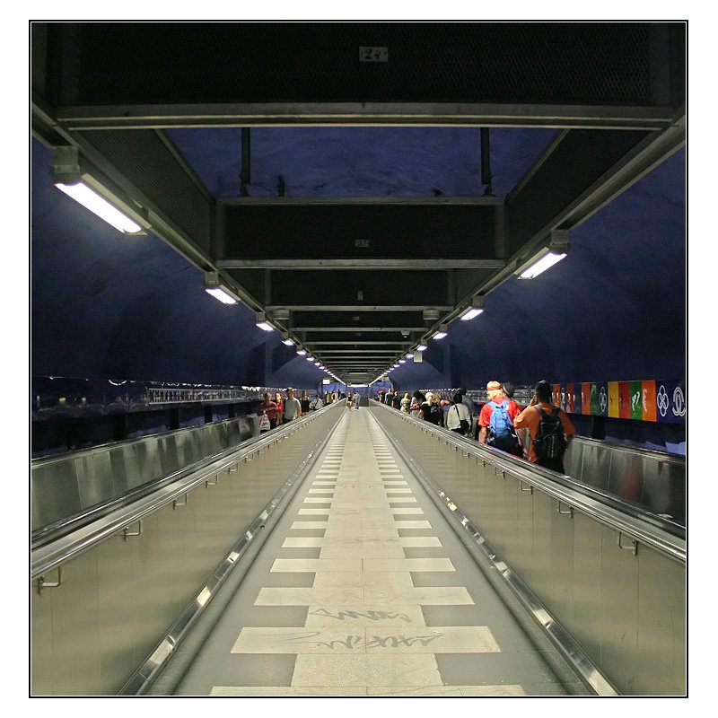 Blaue Linie, Stammstrecke, Station  T-Centralen  -

Der Bahnhof der Blauen Linie bildet zusammen mit dem Stationsteil der beiden anderen Linen ein V. Die Spitze befindet am Ausgang Sergels Torg. Etwa in Bahnsteigmitte beider Stationen befindet sich dieser über 100 Meter lange leicht schräge Gang mit Fahrsteigen für die Umsteiger von und zur blauen Linien. 

24.08.2007 (M)