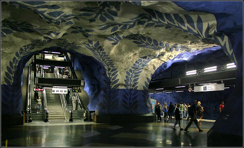 Blaue Linie, Stammstrecke, Station  T-Centralen  - 

Blick in die Bahnsteigebene dieses Bahnhofes mit der auffälligen Bemalung der Spritzbetonflächen. Die Treppeanlag führt zu dem Verbindungstunnel, der mit die Blaue Linien mit den anderen T-Bahnlinen verbindet. An der Ostseite gibt es einen Ausgang zum Sergels Torg, an der Westseite zum Bahnhof Stockholm C. Die Bahnsteige der Blauen Linie liegen hier 29 Meter unter der Oberfläche bzw. 24 Meter unter Meeresoberfläche. Darunter soll noch eine viergleisge Station für den Pendeltåg entstehen. Als erste Strecke der Blauen Linie ging am 31.9.1975 der Abschnitt T-Centralen - Hallonbergen - Hjulsta in Betrieb. 

24.8.2007 (M)