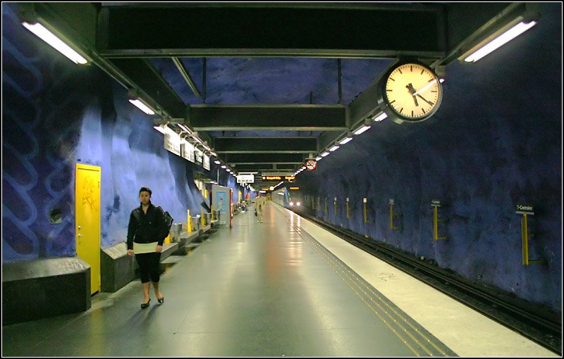 Blaue Linie, Stammstrecke, Station  T-Centralen  - 

Blick in einer der Bahnsteigröhren. Im Gegensatz zur Roten Linie wurde bei den Gewölbestationen der Blauen Linie auf das Gitter über den Bahnsteigen verzichtet und die Beleuchtung und sonstige Ausrüstungen an einem Rost von der Decke abgehängt. Dieser und sämtliche weiteren Bahnsteigeinbauten sind Standard aller in den siebziger Jahren gebauten Tunnelstationen dieser Linie. Unterscheidungen ergeben sich in der Hauptsache durch die Farbgebung der Spritzbetonflächen und der weiteren künstlerischen Gestaltung. 

22.08.2007 (M)