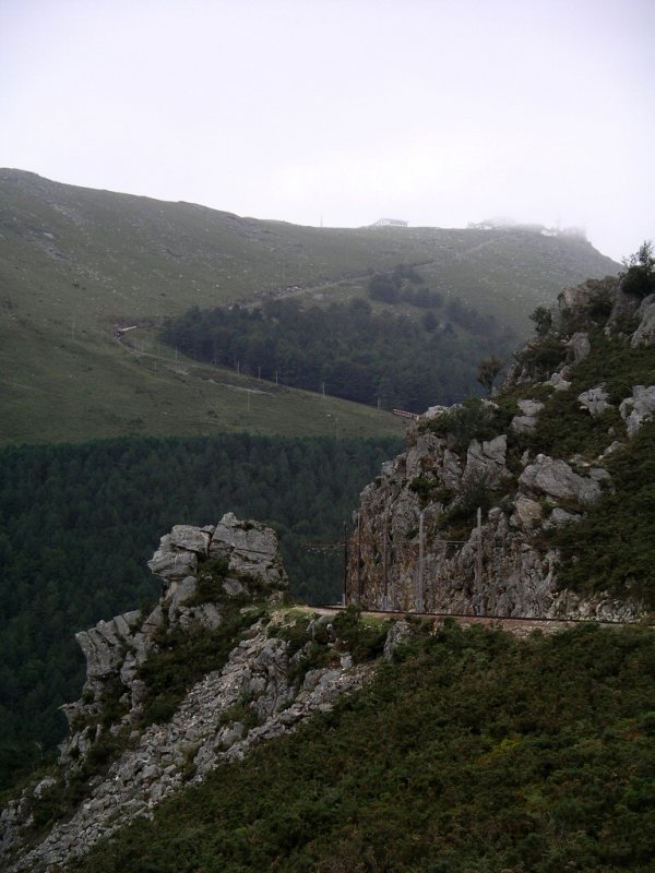Blick auf den steilen Teil der Strecke hoch zum Gipfel, auf dem zwei Zge unterwegs sind. 
Die Bahn bewltigt einen Hhenanstieg von 736 m. Die Bergstation liegt auf 905 m Hhe. Direkt auf dem Gipfel, welcher an diesem Tag leider etwas neblig war, verluft die Staatsgrenze zwischen dem franzsischen und dem spanischen Teil des Baskenlandes.
23.09.2004