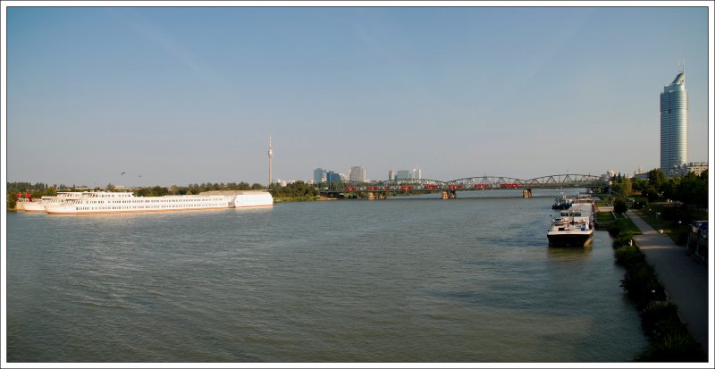 
Blick auf die Wiener UNO-City mit Donauturm und links auf den 202 Meter hohen (mit Turmspitze) Millenium Tower am Wiener Handelskai. Vielleicht interessant: Die Verglasung des Millenium Tower hat eine Flche von 15.000 qm. So nebenbei quert auch ein Regionalzug die Donau und wird nur Sekunden spter in der Station Wien Handelskai halten.

Die Aufnahme besteht aus zwei Fotos. Da ich den Fehler (falls man es als Fehler sehen kann) gemacht habe, das zweite Foto gleich nach der ersten Aufnahme zu machen, hat diese DoSto Garnitur 7 statt 5 Waggons. Naja, so wird halt der Zug etwas lnger
