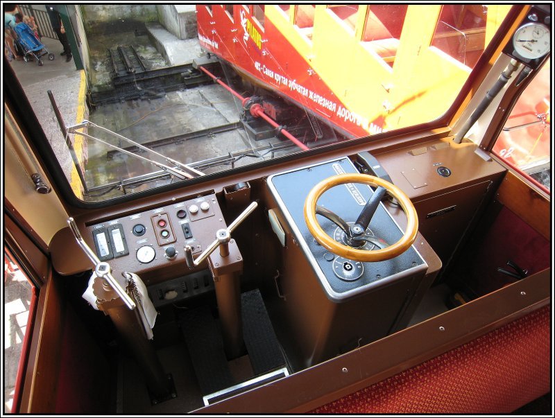 Blick von meinem Platz im Fahrgastraum auf den karg ausgestatteten Fhrerstand eines Triebwagens der Pilatus-Bahn. Im Hintergrund ist der Unterbau der Schiebebhne zu erkennen, auf der die Triebwagen in der Talstation das Gleis wechseln knnen. Rechts steht gerade ein Wagen auf der Bhne. (19.07.2007)  