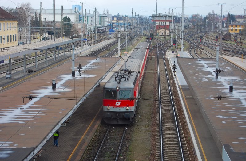 Blick von der neuen Bahnsteigberfhrung des Hauptbahnhofes von Wels. Einfahrt erhlt eine Nahverkehrsgarnitur angefhrt durch 1044 055-0. Im Hintergrund das sogenannte historische  Schirmstellwerk . Die Gleise rechts fhren in die Gterzugumfahrung und weiter zum BB-Terminal Wels, welches hauptschlich Container-Umschlag betreibt.