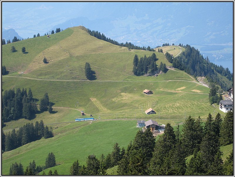 Blick von der Station auf der Rigi Kulm hinunter auf die Strecke, die von Arth-Goldau hinauf zur Rigi fhrt. Der Zug, der dort gerade bergauf unterwegs ist wird als nchstes die Station Rigi Staffel erreichen. (20.07.2007)