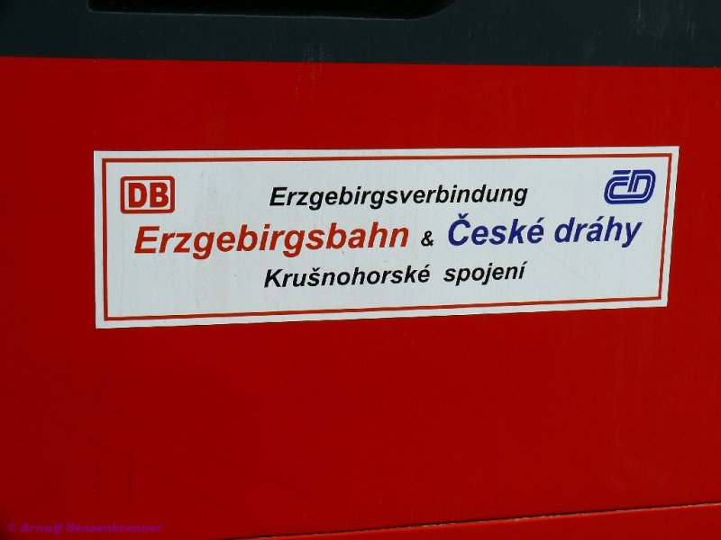 BoG = Bahn ohne Grenzen.
Werbung f�r die Erzgebirgsverbindung von DB-Erzgebirgsbahn und CD in deutsch und tschechisch am 642 der DB-Erzgebirgsbahn. 
Erst seit 1993 findet auf der Strecke von Chemnitz �ber B�renstein und Vejprty (Weipert) nach Chomutov (Komotau) wieder grenz�berschreitender Verkehr statt. Nach dem Kriegsende 1945 war dies nicht mehr der Fall. Am 01. August 1993 wurde der grenz�berschreitende Reisezugverkehr von B�renstein nach Vejprty wieder aufgenommen.  
Leider werden auch in Tschechien die Mittel f�r den Bahnverkehr gek�rzt und seit Dezember 2007 wurde der wochent�gliche Reisezugverkehr von Chomutov nach Vejprty durch den verantwortlichen �steck� kraj (Bezirk Usti=Aussig) abbestellt. Als Grund f�r die Einstellung wurde vor allem die geringe Auslastung der Z�ge genannt. Seither gibt es auf tschechischer Seite nur noch touristisch orientierten Verkehr an den Wochenenden. Von Vejprty nach Chemnitz kann man mit den Z�gen der deutschen Erzgebirgsbahn aber weiter t�glich fahren! 






