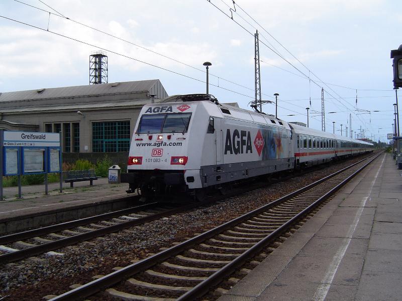 BR101 083-4 zieht hier ihren IC2410 auf dem Weg von Leipzig ber Berlin nach Stralsund in den Greifswalder Hbf. Aufgrund der AGFA-Werbung ist die Lok aus weiterer Entfernung kaum von den IC-Wagen zu unterscheiden - sozusagen ein Chamleon auf deutschen Schienen. Leider beginnt die Klebefolie sich bereits im Bereich der unteren Spitzenlicht-Scheinwerfer abzulsen. Dieses Bild entstand am 20.08.04