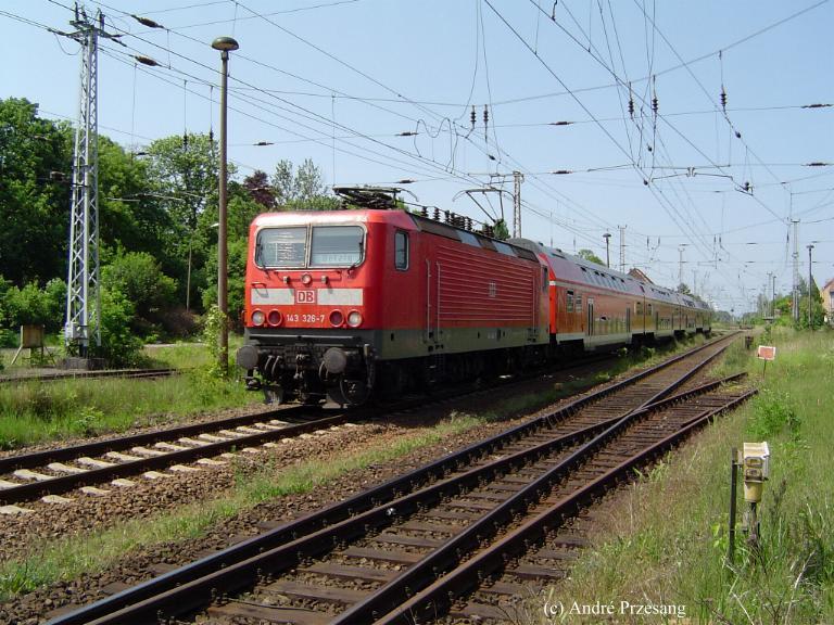 BR143 326 mit einem RE aus Stralsund kommend kurz vor dem Greifswalder Hbf. Wenn man genau hinschaut, dann entdeckt man im linken Frontfenster der Lok die feinen Heizstreifen, womit im Winter die Scheiben beheizt und somit eisfrei gehalten werden knnen!  (02.06.03)