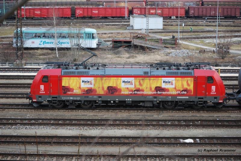 Breitseite: 185 586-5 (Lok 2054 der HGK) erreicht mit ihrem Kesselwagenzug am 27.02.09 Ulm. Von hier werden die Zge in der Regel mit Class 66 der HGK auf nicht elektrifizierten Strecken weitertransportiert. Im Hntergrund ein Beiwagen des  Ulmer Spatz .