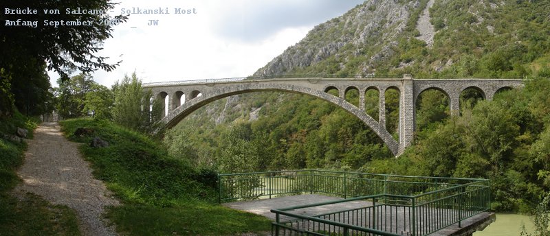 Brcke von Salcano / Solkan. Diese Brcke war fr lange Zeit der lngste Bruchsteinviadukt der Welt - zuerst von 1906, wo er binnen 18 Monaten errichtet wurde, die gut 80 Meter Spannweite hat man mit einem Hilfspfeiler in der Mitte berbrckt und in 18 Monaten die Brcke errichtet (und die Baukosten eingehalten). Bis in den Ersten Weltkrieg hinein war diese Brcke dann eben der lngste Bruchsteinbogen der Welt, dann nicht mehr, nicht weil jemand anderer einen lngeren gebaut htte, sondern weil sterreich-Ungarn auf dem Rckzug das Ding umgefeuert hat, um den Mittelbogen nach der Rckeroberung durch eine Kohn'sche Stahlbrcke zu ersetzen, die im weiteren Verlauf ihre Aufgabe recht gut erfllt hat, die ganze Zeit im SHS-Staat. Irgendwann in den 30ern ist die Gegend dann italienisch geworden, woraufhin das faschistische Regime den Steinbogen wieder aufgerichtet hat. Dann war die Brcke wieder die lngste der Welt, bis in den 60er-Jahren in China eine lngere gebaut wurde. Heute liegt die Brcke einige wenige Kilometer von der slowenisch-italienischen Grenze, man hat hier einen schnen, kleinen Park errichtet und anllich des hundertjhrigen Jubilums der Errichtung eine Gedenktafel angebracht, es gibt eine kleine Aussichtsplattform und etwas abseits, beim Parkplatz, ein schnes, kleines Grillrestaurant, das wohlschmeckende und fleischbetonte Kost bietet. Anfang September 2009 kHds - das Panorama ist aus fnf Bildern von Hand zusammengesetzt.