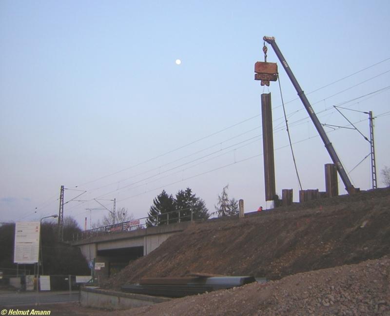 Da das s�dliche Streckengleis aufgrund der Arbeiten f�r die neue S-Bahn-Station in Frankfurt am Main-Zeilsheim gesperrt werden mu�te und dies betrieblich wahrscheinlich nicht im Berufsverkehr montags bis freitags durchgef�hrt werden konnte, wurden am Sonntag den 12.03.2006 an der Baustelle noch nach 18 Uhr Spundw�nde in den Boden gerammt. Die Anwohner werden davon bestimmt nicht begeistert gewesen sein bei den heftigen Vibrationen, die ich auch unter den F��en sp�rte.