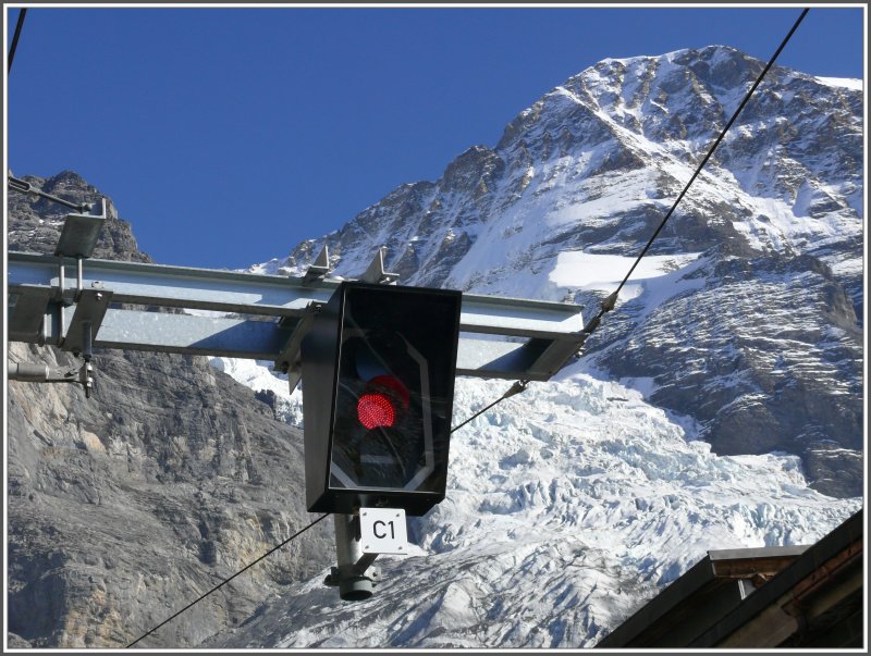 Das Ausfahrsignal (LED Lampen) in Eigergletscher Richtung Jungfraujoch zeigt rot. Der Mnch thront als mchtige Kulisse ber dem Gletscher und dem letzten Bahnhof vor dem Tunnel.
(11.10.2007)