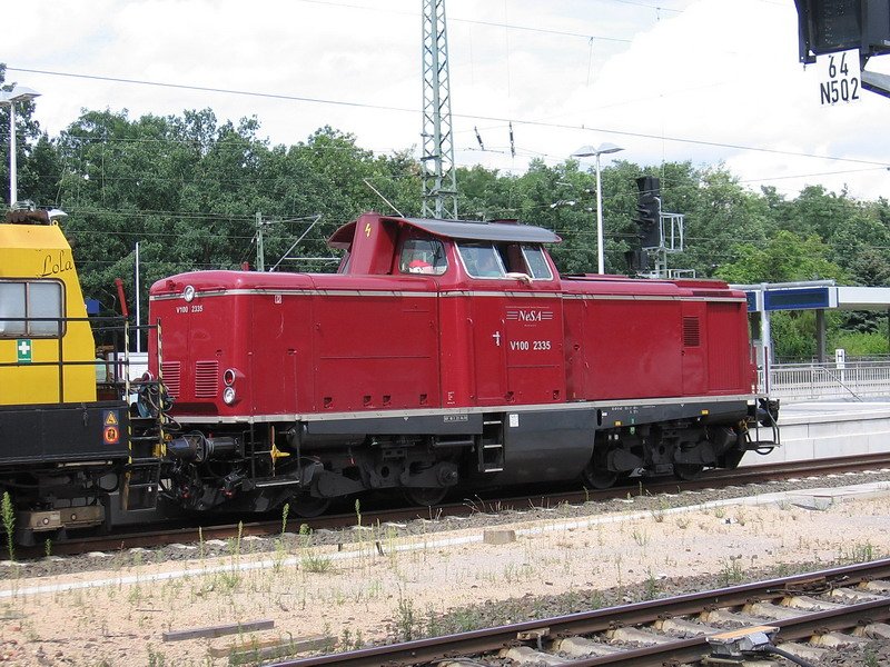 DB V100 in altrot der NeSa wartet mit einen Schienenschleifzug in Frankfurt/Main-Stadion auf die Freigabe nach F-Louisa.