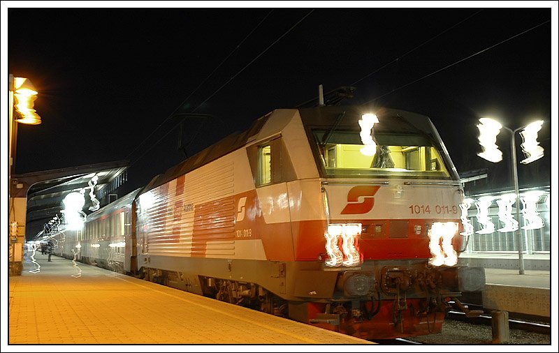 Der Abend des 26.1.2008 in Wien. Die Vorlufer des Sturmtiefs „Paula“ haben bereits Wien erreicht. Es war mir nicht mglich, 1014 011 vor der Abfahrt in Wien mit dem EC 70 „Antonn Dvork“ nach Prag verwacklungsfrei aufzunehmen. Vom anderen Bahnsteig aus war ein Foto leider berhaupt nicht mglich, diese Bahnsteigaufnahme hat aber meiner Meinung was. Ich wollte ein „Windloch“ nutzen, aber kurz, bevor der Verschluss zugemacht hat, hat sich die Kamera durch den Sturm nach vorne geneigt. Was mich nmlich bei dieser Aufnahme selber wundert ist, dass es das einzige scharfe Foto von 10 Bildern von dieser Situation wurde, sieht man jetzt von den verzerrten Lichtern ab.