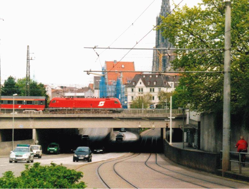 Der EC  Mozart , gefhrt von einer sterreichischen 1016, verlsst am frhen Nachmittag des 23. April 2002 Ulm Hbf zur Weiterfahrt nach Augsburg und Mnchen. Vorn die Schienen der Ulmer Straenbahn (1000 mm), im Hintergrund das Ulmer Mnster.