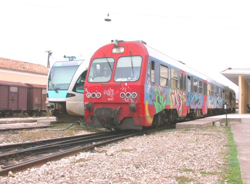 Der IC23 nach Korinth verlsst in einem fragwrdigen Erscheinungsbild den Bahnhof Pirgos. (30.10.2006)Im Gegensatz dazu verkehren die parallel fahrenden modernen Linienbusse in einheitlichem Grn.