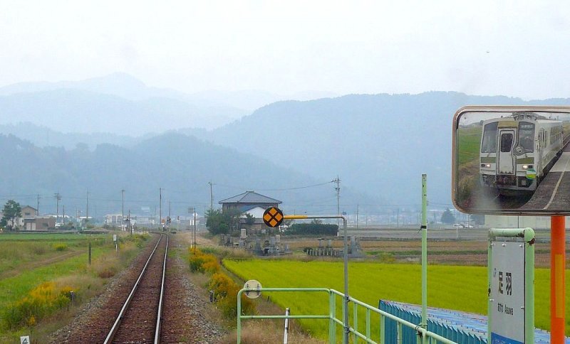 Der KIHA 120-202 der Kuzuryû-Linie - ein Spiegel-Bild: Der Wagen fährt von Norden her auf die hohen, wilden Berge zu. Rechts der Gleise etwas weiter vorn sieht man Gräber. Asuwa, 3.November 2008. 