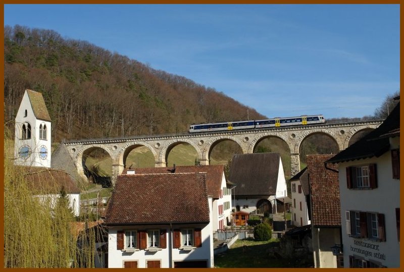 Der Regionalzug von Olten ist nach Sissach unterwegs und hier kurz vor der Station Rmlingen (Kanton Baselland). Die kleine Bahnstation befindet sich links neben dem Kirchturm und zu Fuss etwas mhselig zu erreichen. Die wunderschne Steinbrcke ist sicher ein Wahrzeichen des Ortes. 12.3.2007