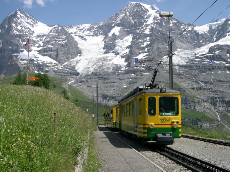 Der Triebwagen 124 der Wengernalpbahn ist am 28.06.2005 mit seinem Beiwagen in Richtung Kleine Scheidegg unterwegs. Im Hintergrund das mchtige Jungfraumassiv.