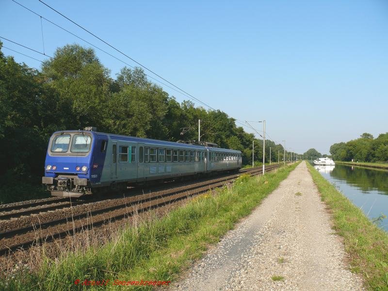 Der Triebzug Z15501 (Typ Z2) ist hier unterwegs als nur an Samstagen verkehrender Bummel-Regionalzug TER30168 von Strasbourg (ab17:58) nach Saverne(an18:58).
Hier in Steinbourg verlaufen die Vogesenstrecke und der Rhein-Marne-Kanal direkt parallel.

04.08.2007 Steinbourg

