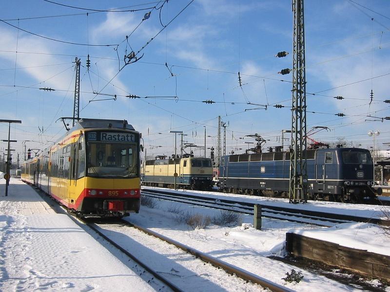 Der verschneite Hauptbahnhof Karlsruhe am 30.12.2005. Im Bild eine Zweisystem-Stadtbahn des Karlsruher Verkehrsverbundes (KVV) mit Triebwagen 895, die als S32 mit Ziel Rastatt bereitgestellt wird, auerdem zwei abgestellte Loks der BR 181. 